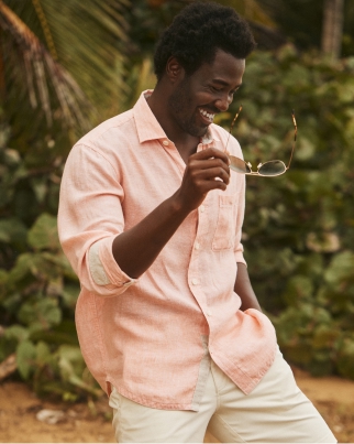 Man in a light shirt holding sunglasses