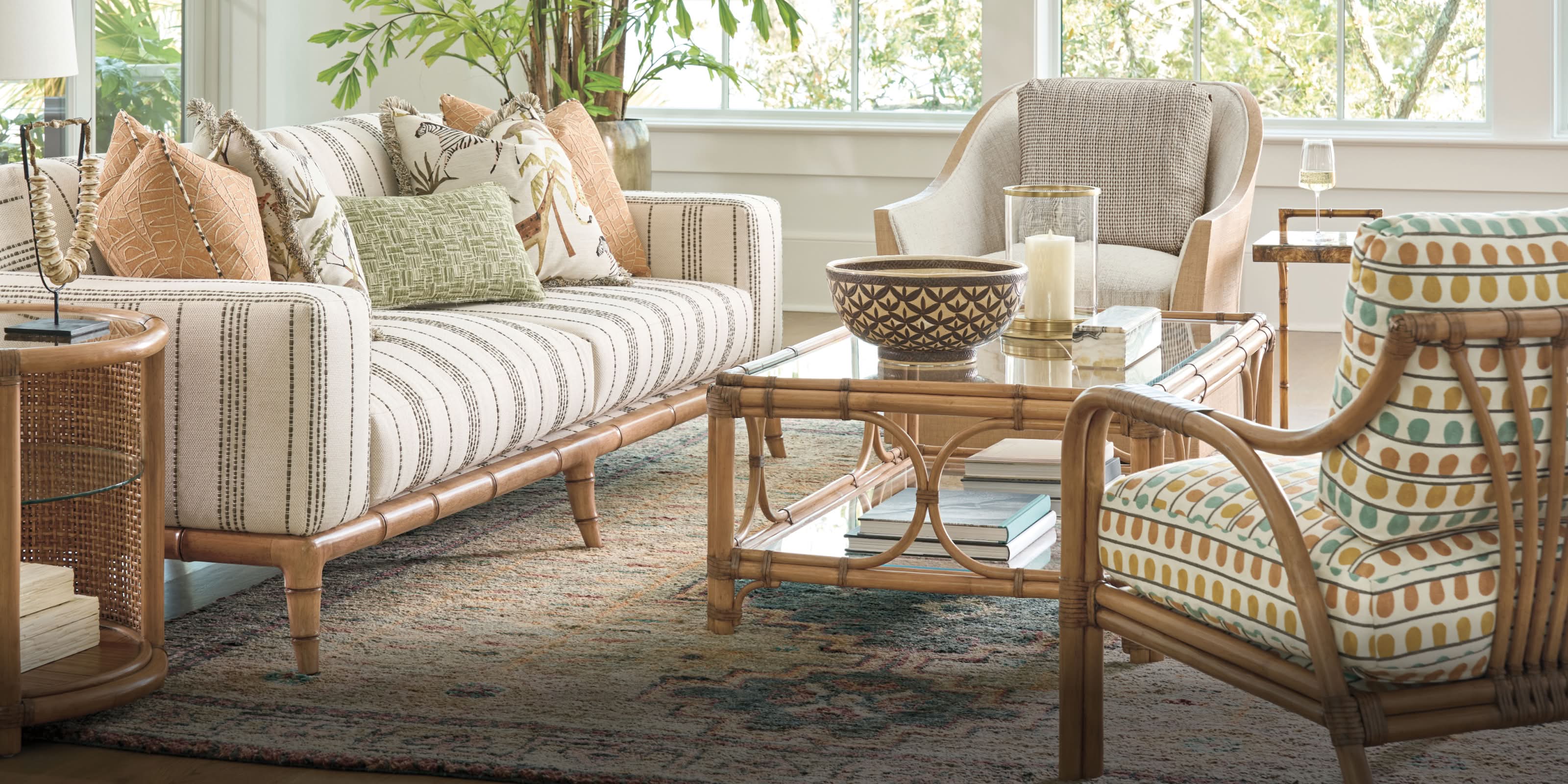 A living room with neutral striped seating, a rattan coffee table, and patterned accent chair